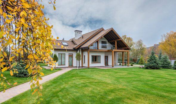 Modern home with a landscaped yard, featuring a pathway, trees, and autumn foliage, representing ideal properties for buyers in Mt. Pleasant, MI.